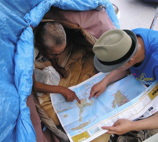 自分の生まれた場所を地図で指す沖縄出身のホームレス男性（左）＝２０１３年５月、川崎市幸区で（川崎野宿者聞き取りチーム提供）