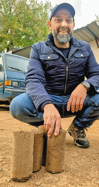 レバノン北部コーラで2022年12月、固形燃料ピートの説明をするシェイクさん=蜘手美鶴撮影