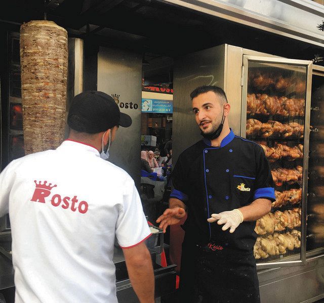 １１日、カイロ近郊で、ケバブ店で働くシリア人のオクパ・フサインさん（右）＝蜘手美鶴撮影