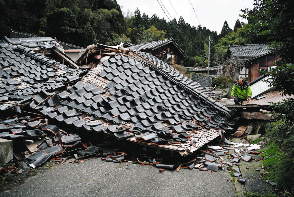 倒壊し道路を塞ぐ家屋。地中に水道管があると工事できない＝7日、石川県輪島市長井町で