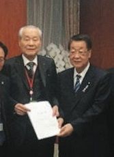 ２０１８年11月１２日、農林水産省の大臣室で吉川貴盛農相（右）に要望書を渡すアキタフーズの秋田善祺元代表（左）