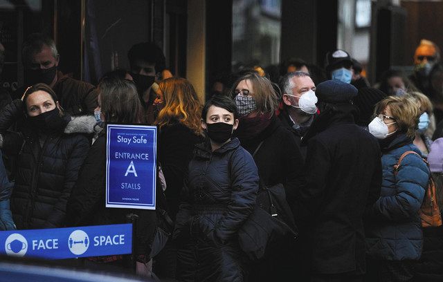 マスクを着けて劇場前に並ぶ人々＝２８日、英国ロンドンで（ＡＰ）