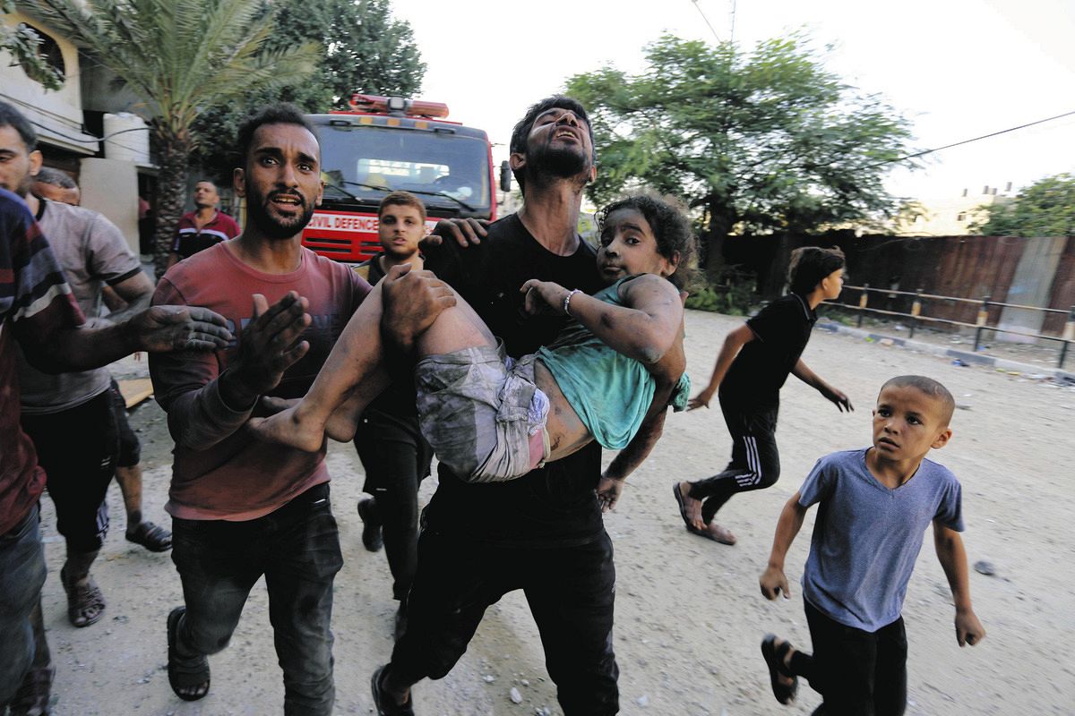 イスラエル軍の空爆で負傷した少女を運ぶ人々