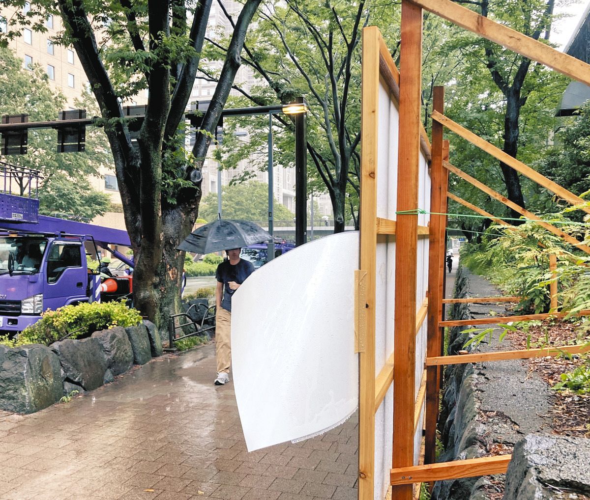 都庁近くの掲示場で枠外に張られたポスター。クリアファイルに入れられ、雨で下を向いていた＝21日、東京都新宿区で（奥野斐撮影）