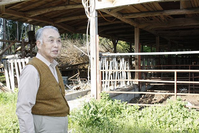 牛がいない牛舎の前で、１０年を振り返る坂本勝利さん＝福島県富岡町で 