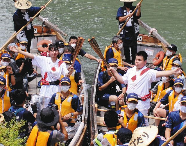 「ライン下り」の舟上で聖火のトーチキスをする相沢さん（右）と小林さん（左）＝長瀞町の荒川で
