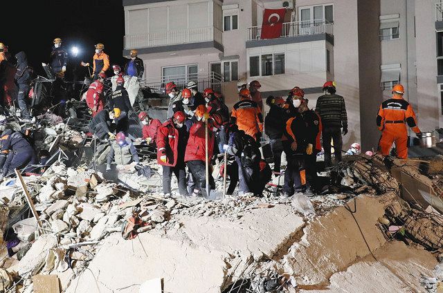 ３１日、トルコ西部イズミル県で、地震により建物が倒壊した現場周辺を捜索する救助隊員ら（ゲッティ＝共同）