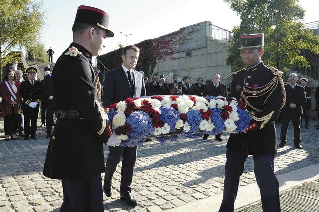 １６日、パリ西郊での式典で献花するマクロン大統領（中央）＝ＡＰ