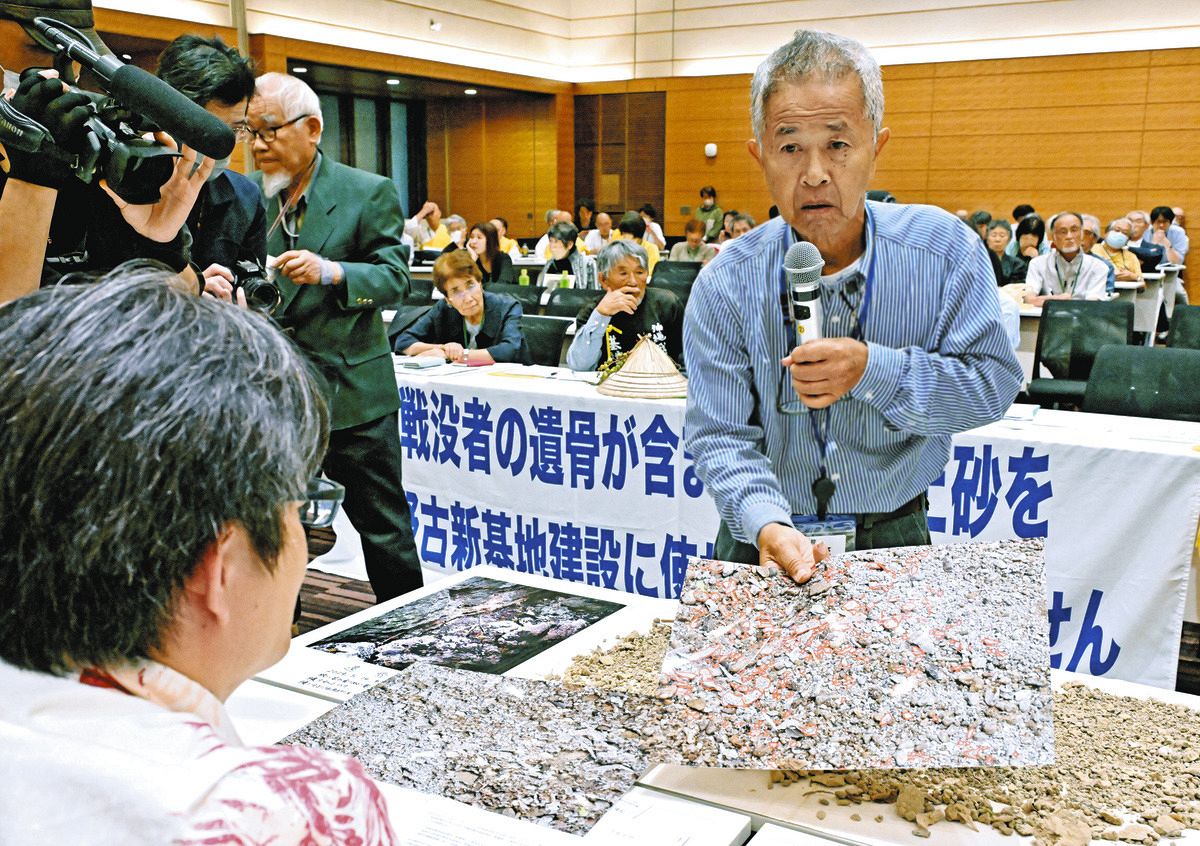 遺骨が混じった沖縄本島南部の土砂を持ち込み防衛省の職員（手前）に説明する具志堅隆松さん