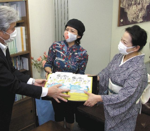 高橋雄幸教育長（左）に書籍と絵本を手渡す犬飼このりさん（中）と関川永子さん＝伊東市役所で

