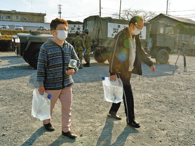 自衛隊から給水された飲料水を運ぶ中塚武さん（右）、芳子さん夫妻＝１４日、福島県新地町で
