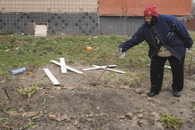 ロシア軍に殺害された男性の遺体が埋められた場所を示すキーウ近郊ブチャの住民（AP）