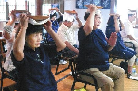 灸が乗った焙烙を頭に当てる参加者たち＝沼田市の妙光寺で