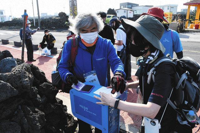 １４日、韓国・済州島で、済州オルレのコースに設置されたスタンプを押す参加者＝木下大資撮影