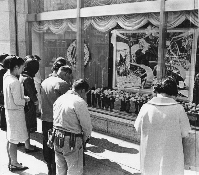﻿デパートのウインドーに据えられた吉田氏の遺影の前で黙とうする人たち＝1967年10月31日、東京・池袋で