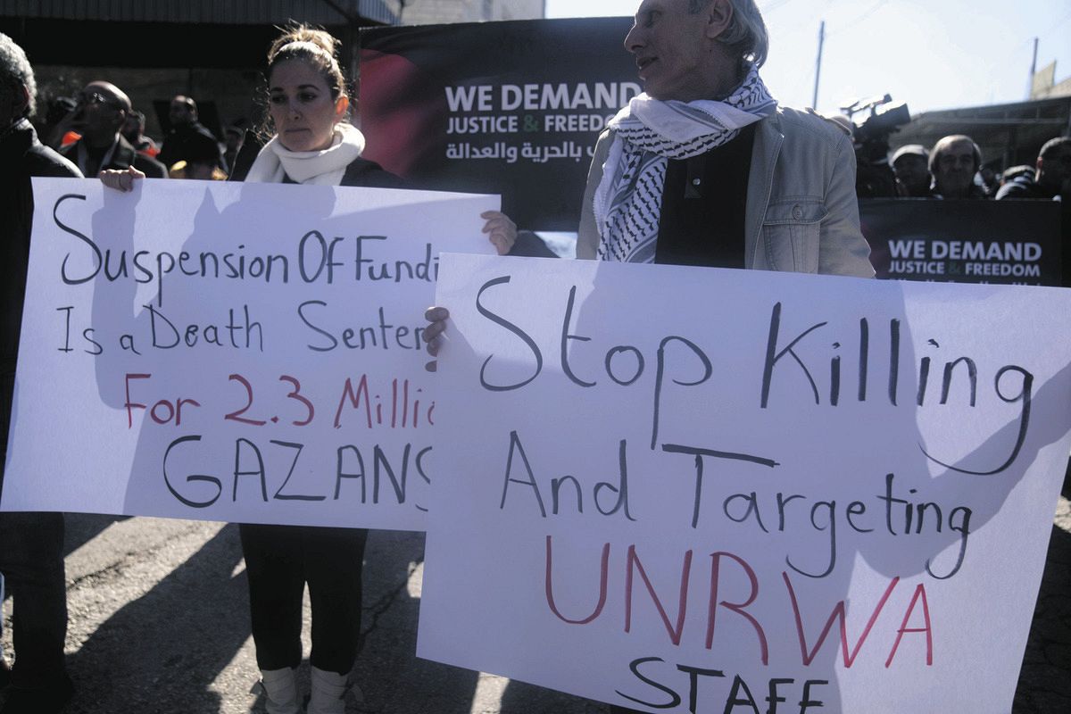 パレスチナ自治区ヨルダン川西岸で7日、「UNRWAへの資金拠出停止に講義し「ガザ市民への死刑宣告だ」というプラカードを掲げる人たち＝AP