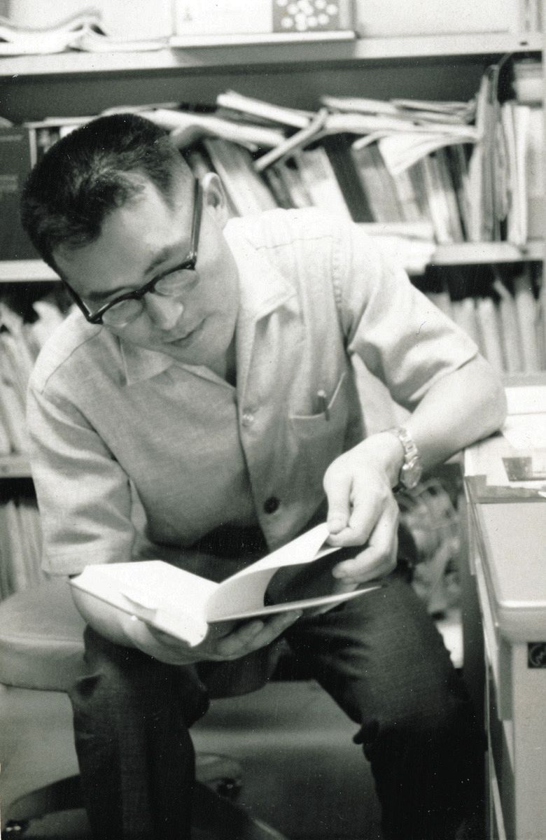 書籍を手に精神科医療史の研究に励む岡田さん＝1960年代撮影、本人提供