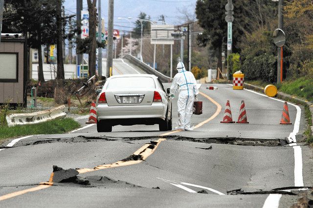 地震で波打った道路には、原発関連企業の社員とみられる人がいた＝福島県大熊町で（豊田直巳さん提供、一部画像処理）