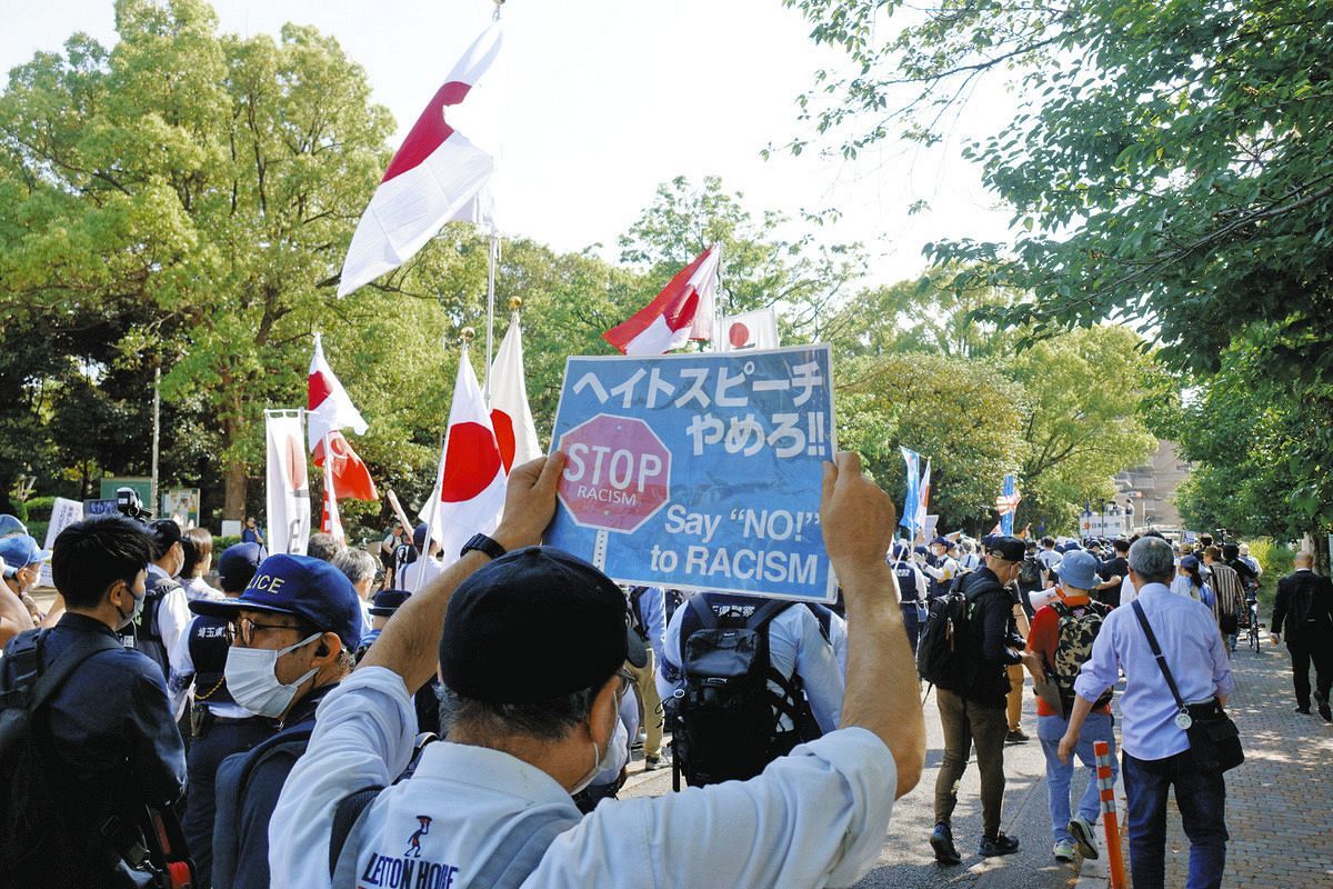 日の丸を振ってデモする人たちに対し、差別反対を訴える男性（手前）ら＝4月28日、埼玉県蕨市で