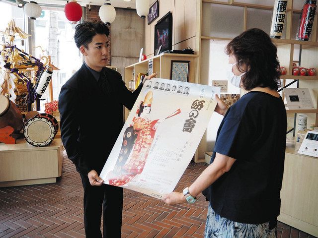店の人にポスターを手渡す尾上右近さん（左）＝台東区で
