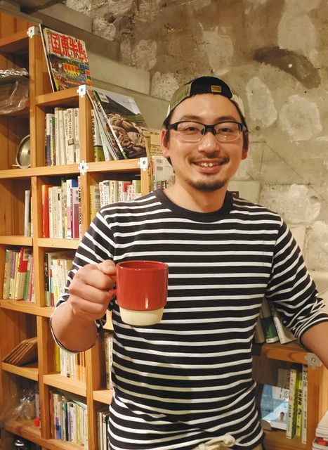 旅をテーマにしたブックカフェの説明をする佐藤亮太さん＝品川区で

