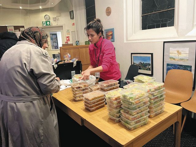 ロンドン市内の教会のウォームバンクで11月末、利用者に持ち帰りの食料を渡すボランティアの女性