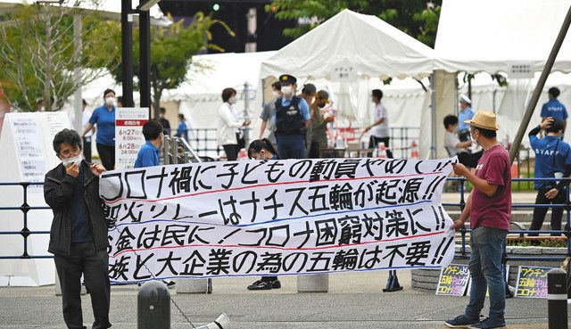 聖火リレーの代替イベント会場前で、横断幕を手に東京五輪中止を訴える人たち
