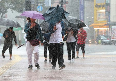 強い雨の中、街を歩く人たち＝１２日午前、東京都渋谷区で