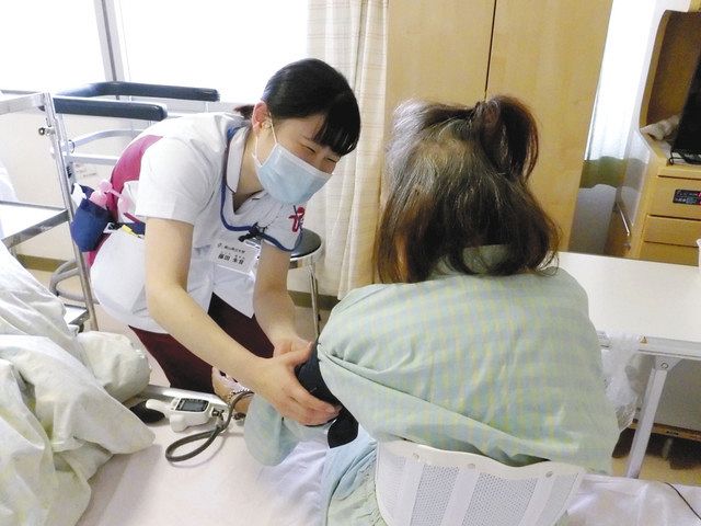 血圧を測りながら患者と視線を合わせて会話する学生（左）＝昨年１２月、富山県内の病院で