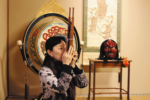 笙を演奏する宮田さん。後方に飾られているのは舞楽「抜頭」で用いる赤い面（一行院所蔵）

