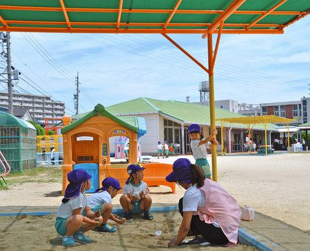 首まで覆う帽子をかぶり、日陰で遊ぶ園児たち＝愛知県豊明市の名古屋短期大付属幼稚園で