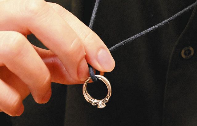 妻・真菜さんの指輪のネックレスを持つ松永拓也さん＝東京都豊島区で