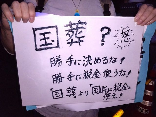 31日、国会前で手書きのプラカードを掲げて抗議の意思を示す参加者