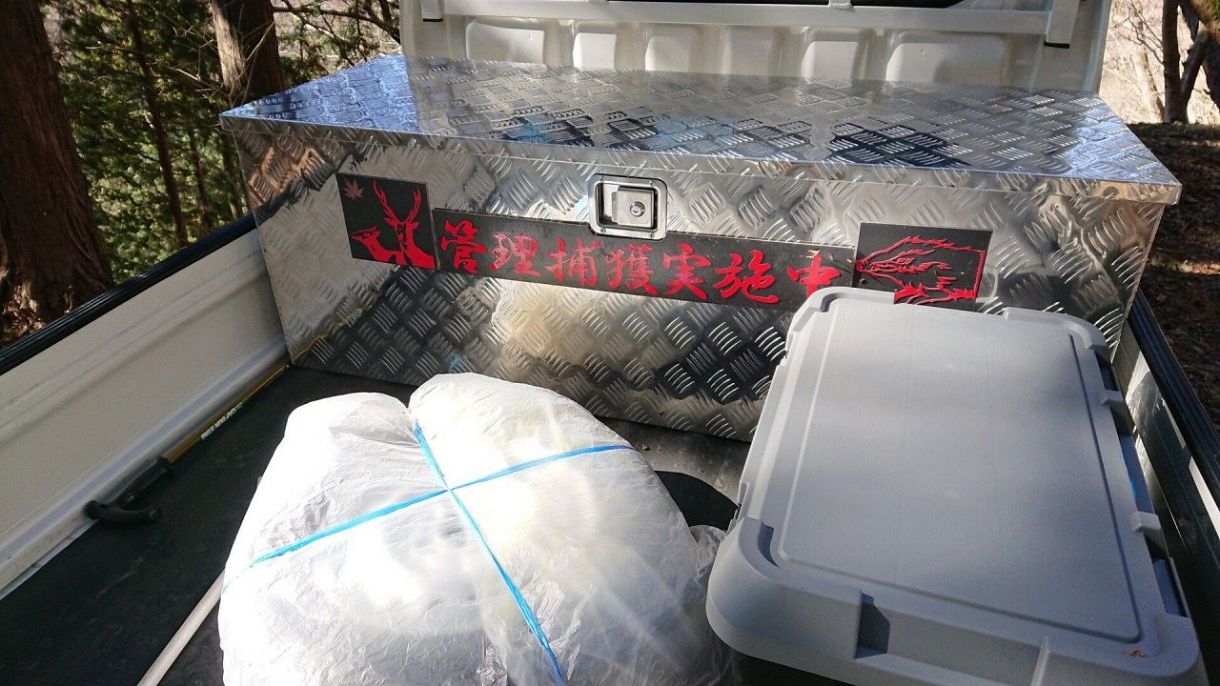 丹沢山地で猟をしていたグループの軽トラの荷台には「管理捕獲実施中」の文字と、シカ、イノシシのイラスト＝2021年2月、神奈川県内で