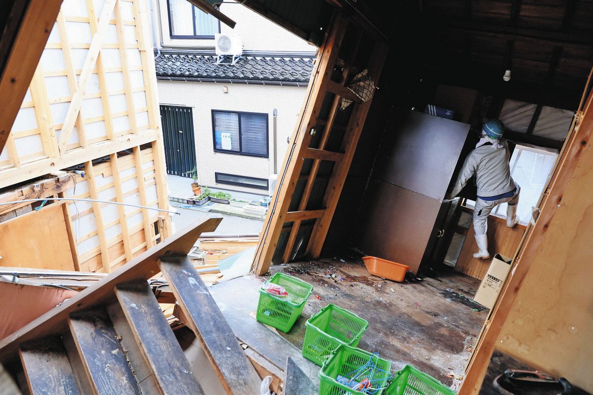 解体を前に、大きく傾いた家屋から物を運び出す作業員＝2月29日、石川県輪島市河井町で