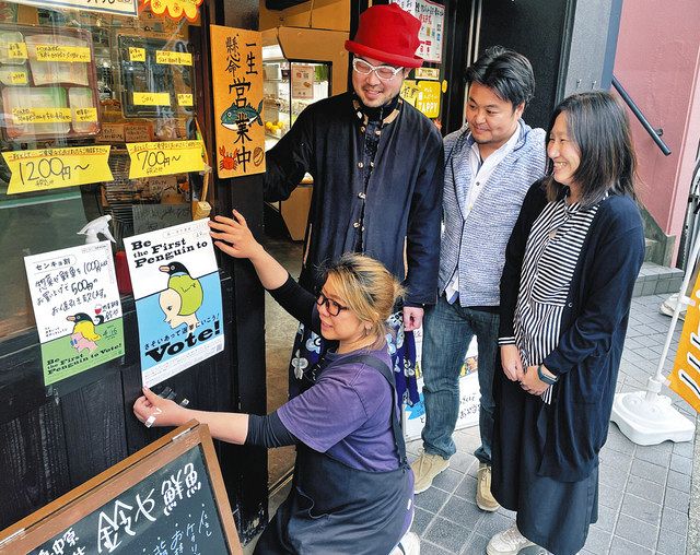 センキョ割ポスターを張る蟹江さん（手前）と団体のメンバー＝いずれも中原区で 