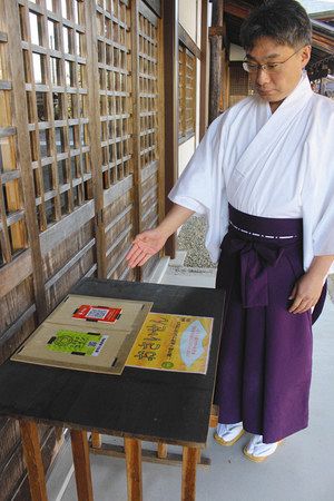 さい銭を受け入れるさるぼぼコイン（手前）と、オリガミペイのＱＲコードを紹介する田中さん＝岐阜県高山市の黄金神社で