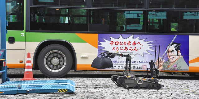 長谷川平蔵をあしらったラッピングバスの前で、遠隔ロボットを使った爆発物対処訓練が行われた＝警視庁本部で