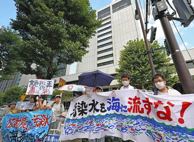 福島第一原発処理水の海洋放出を東京電力ホールディングス本社（後方）に向け、抗議する市民団体ら
