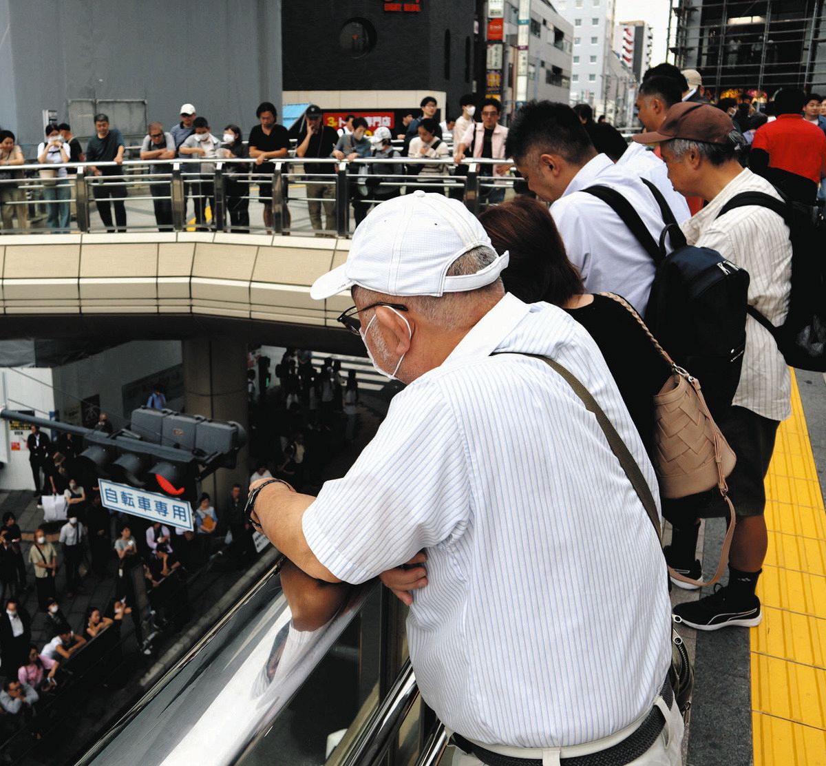 歩行者デッキの上から候補者の演説を聞く人々＝東京都八王子市のJR八王子駅前で