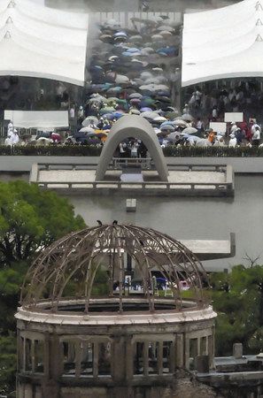被爆から７４年の「原爆の日」を迎え、雨の中、大勢の人たちが訪れた平和記念公園の原爆慰霊碑。手前は原爆ドーム＝いずれも６日午前、広島市で