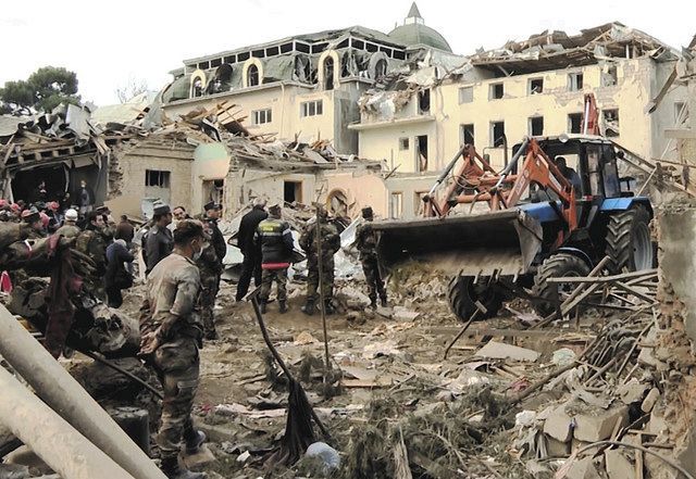11日、アゼルバイジャン西部の中心都市ギンジャで、アルメニアの攻撃を受けた場所を捜索する救援隊員ら＝ＡＰ　