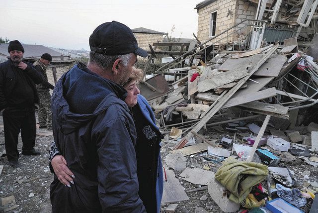 17日、ナゴルノカラバフのステパナケルトで、破壊された建物の前で肩を寄せ合う地元住民ら＝AP