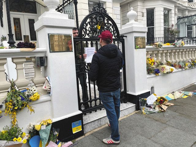 ４日、ロンドンの在英ウクライナ大使館前で、義勇兵の志願者（手前）に手続きを説明する大使館職員＝加藤美喜撮影