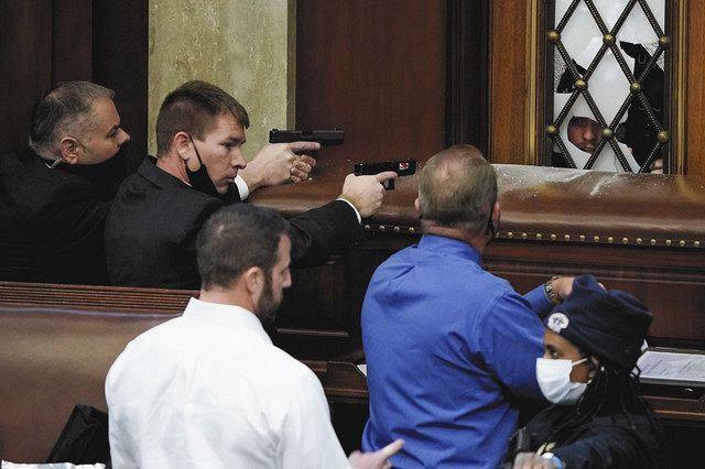 連邦議会議事堂内に侵入しようとするトランプ支持者らに銃を向ける警察官ら＝ＡＰ