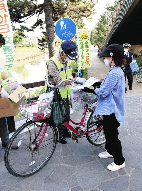 ヘルメット着用を促すチラシを配ったり、自転車に反射材を付けたりする啓発活動＝草加市で
