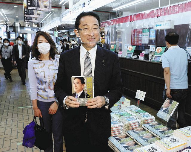 書店に並んだ自身の著書を手にする自民党の岸田政調会長＝１１日午後、東京都内