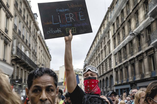 ７日、パリで行われたワクチン接種証明書に反対するデモで複数の言語で「自由」と書かれたボードを掲げる男性＝ＡＰ