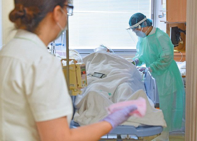 コロナ患者を病室から移動するため準備をする看護師。外では消毒布をもった看護師が待っていた＝千葉市中央区の千葉大病院
