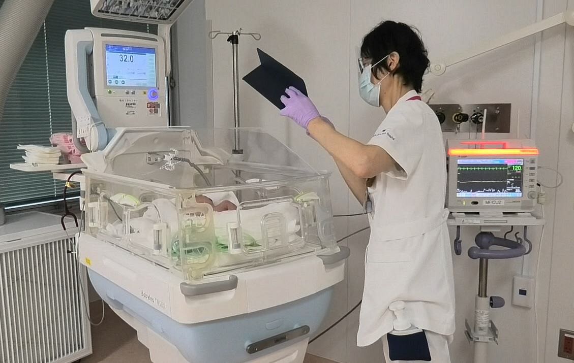 赤ちゃんの写真を撮影する助産師。母子で別々の部屋に入院している＝千葉市中央区で